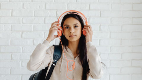 オレンジのヘッドホンで音楽を聴く女の子