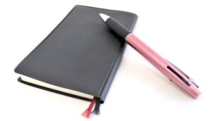 ピンクの多機能ボールペンと手帳